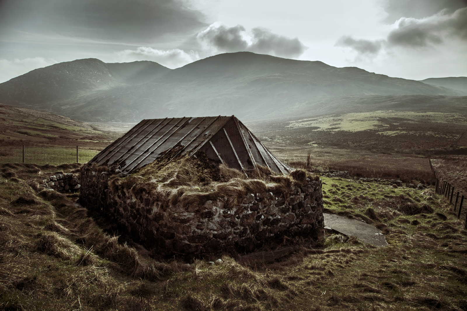 A ruined blackhouse on the machair with the hills of Barra behind