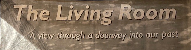 Exhibition banner reading: The Living Room - a view through a doorway into our past